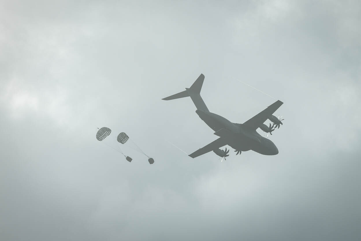 een Duits vliegtuig dropt materieel dat aan een parachute hangt.