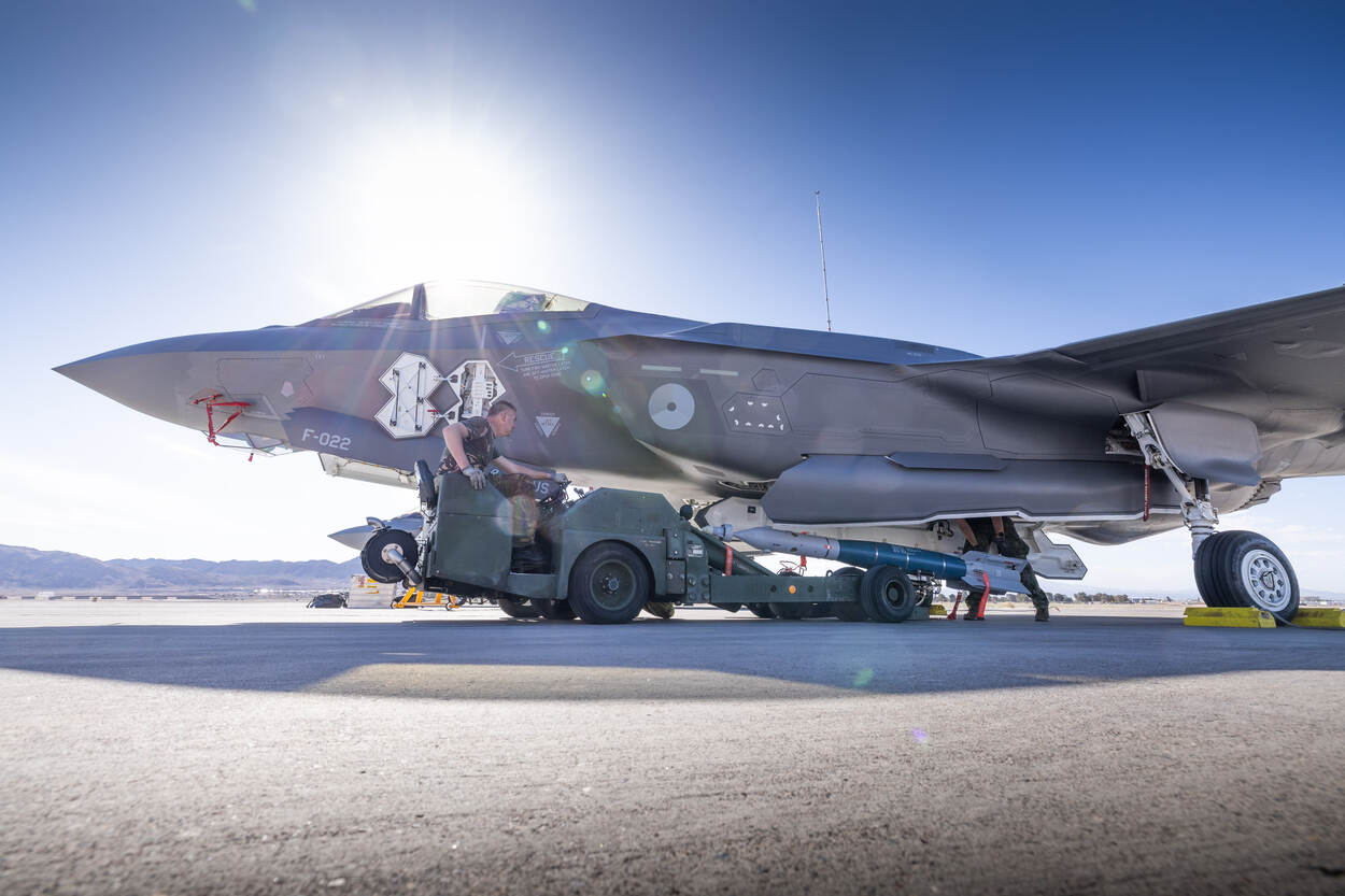 een militair op een speciale heftruck die een bom in het ruim van een F-35 plaatst.