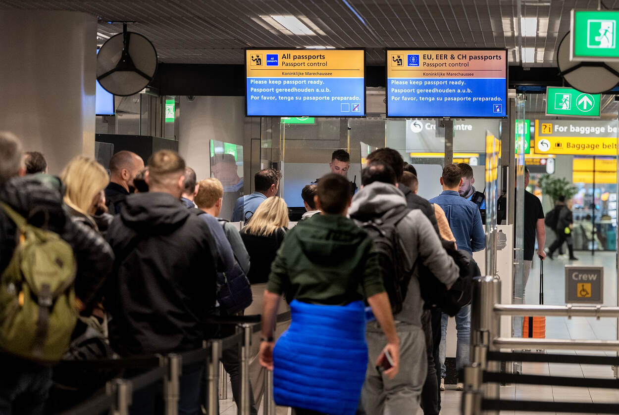 Reizigers in  de rij bij de paspoortcontrole op Schiphol