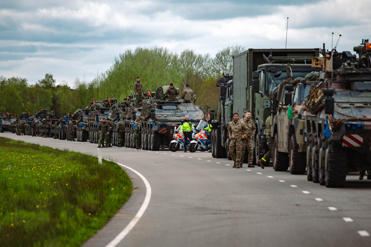 Een colonne met militaire voertuigen staat opgesteld op de weg, klaar om te vertrekken.