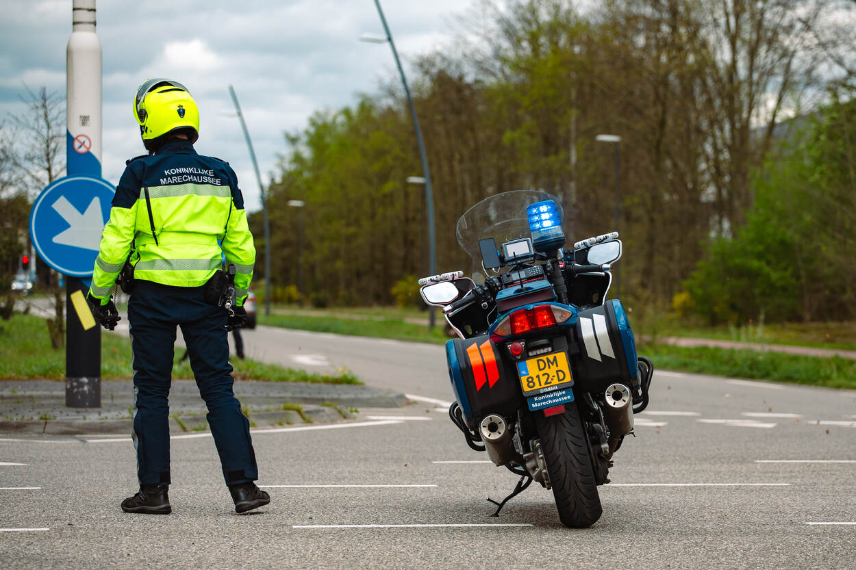 Een motorrijder staat op een kruispunt om verkeer tegen te houden.