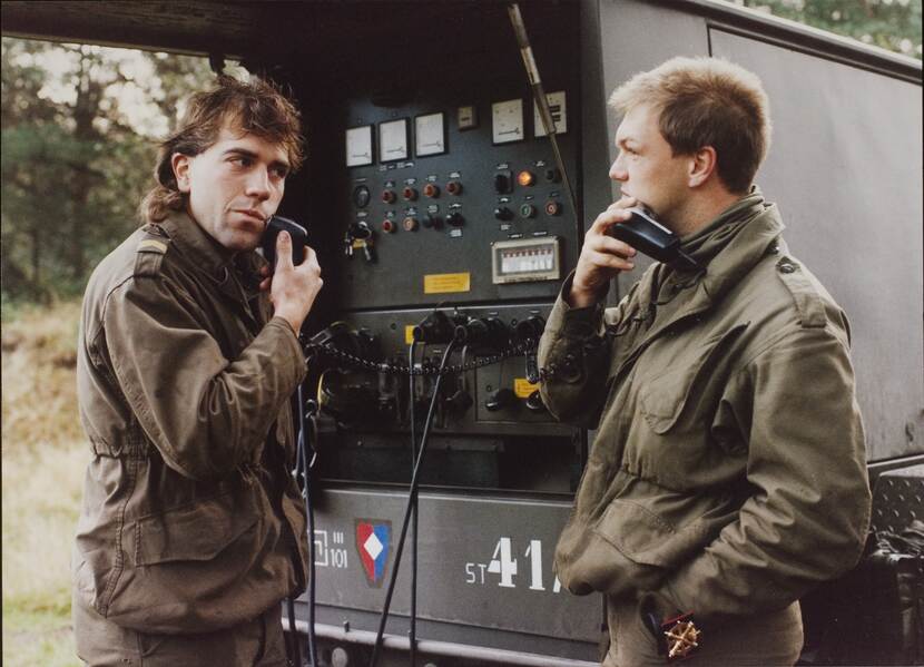 Twee dienstplichten scheren zich met een elektrisch scheerapparaat, aangesloten op de aggregaat, tijdens een oefening in Duitsland in 1990.