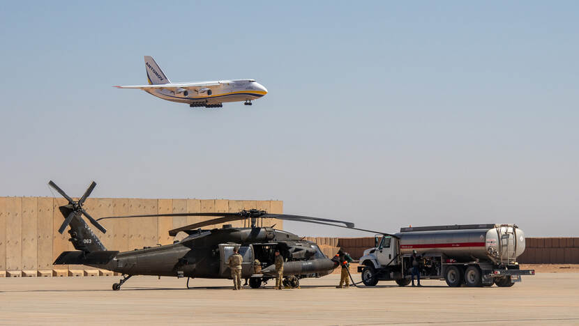 Een Antonov An-124 landt met op de voorgrond een helikopter die getankt wordt vanuit een tankwagen.