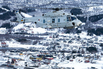 Een NH90-maritieme gevechtshelikopter vliegt over besneeuwd gebied in Noorwegen.