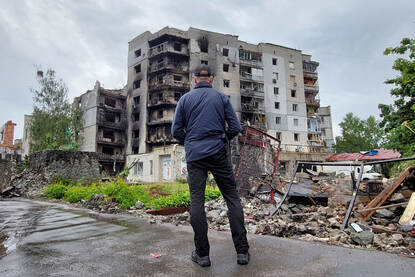 Adjudant Ivo kijkt naar een door oorlog verwoest flatgebouw.