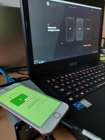 Een aan een laptop verbonden iPhone met een groen scherm, waarop te zien is dat het toestel succesvol is ontgrendeld