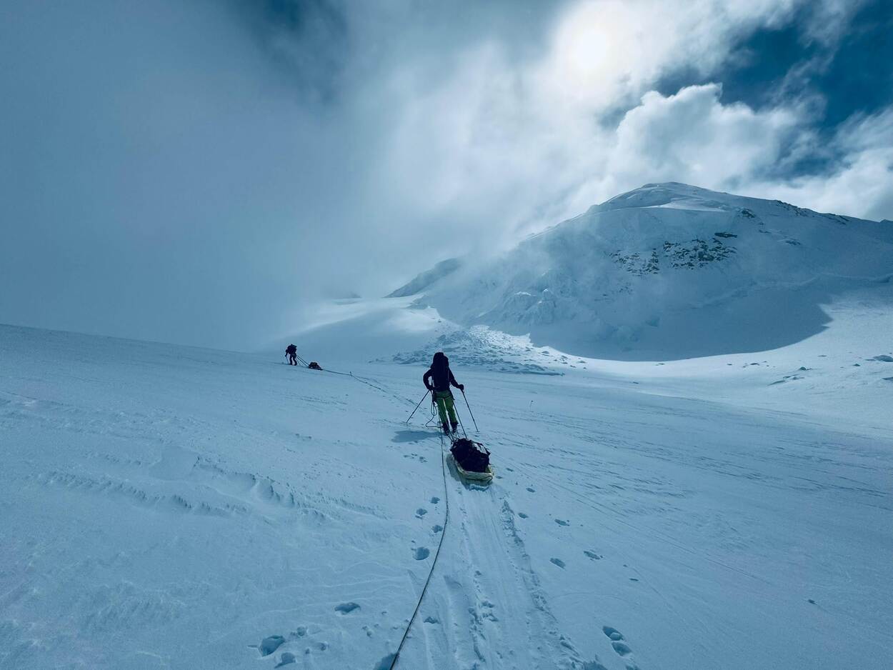 Bergbeklimmer met een slee achter zich aan baant zich een weg over de besneeuwde berg.