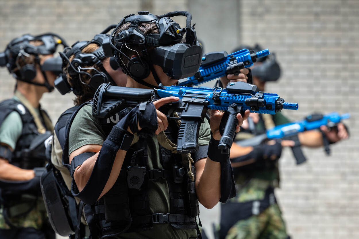 Mariniers met VR-brillen oefenen in een grote, lege fabriekshal met blauwe wapens die bij het SUIT-systeem horen.