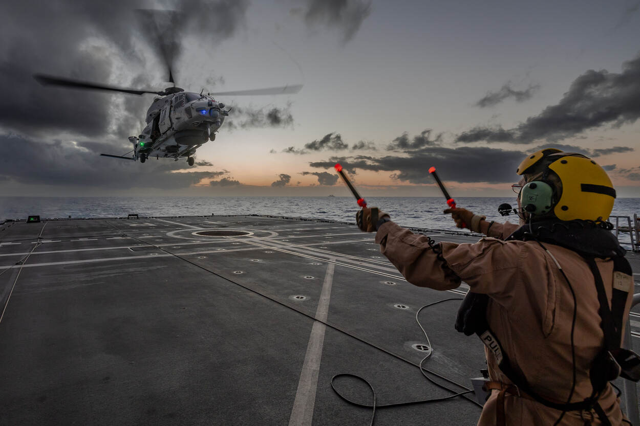 De vliegdekofficier aan boord van Zr.Ms. Tromp geeft met armwuivingen signalen aan de helikopterbemanning van de NH-90 gevechtshelikopter.