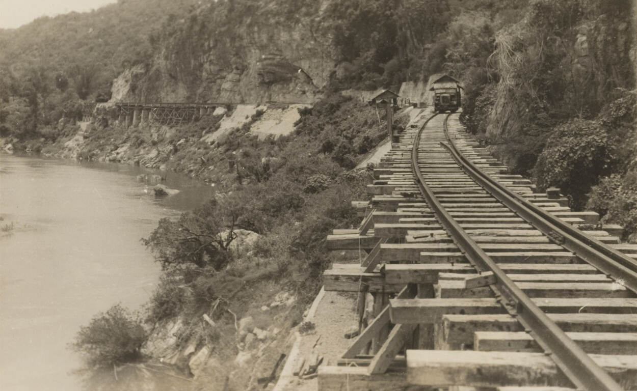 Sepiakleurige foto van een stuk spoorrails langs het water, gemaakt door de gevangenen.