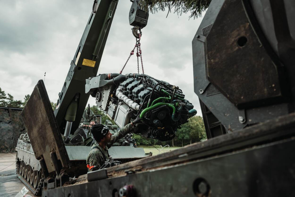 De motor van een CV90 hangt in de takels van een Leopard 2 bergingstank om door de monteurs te worden gerepareerd.