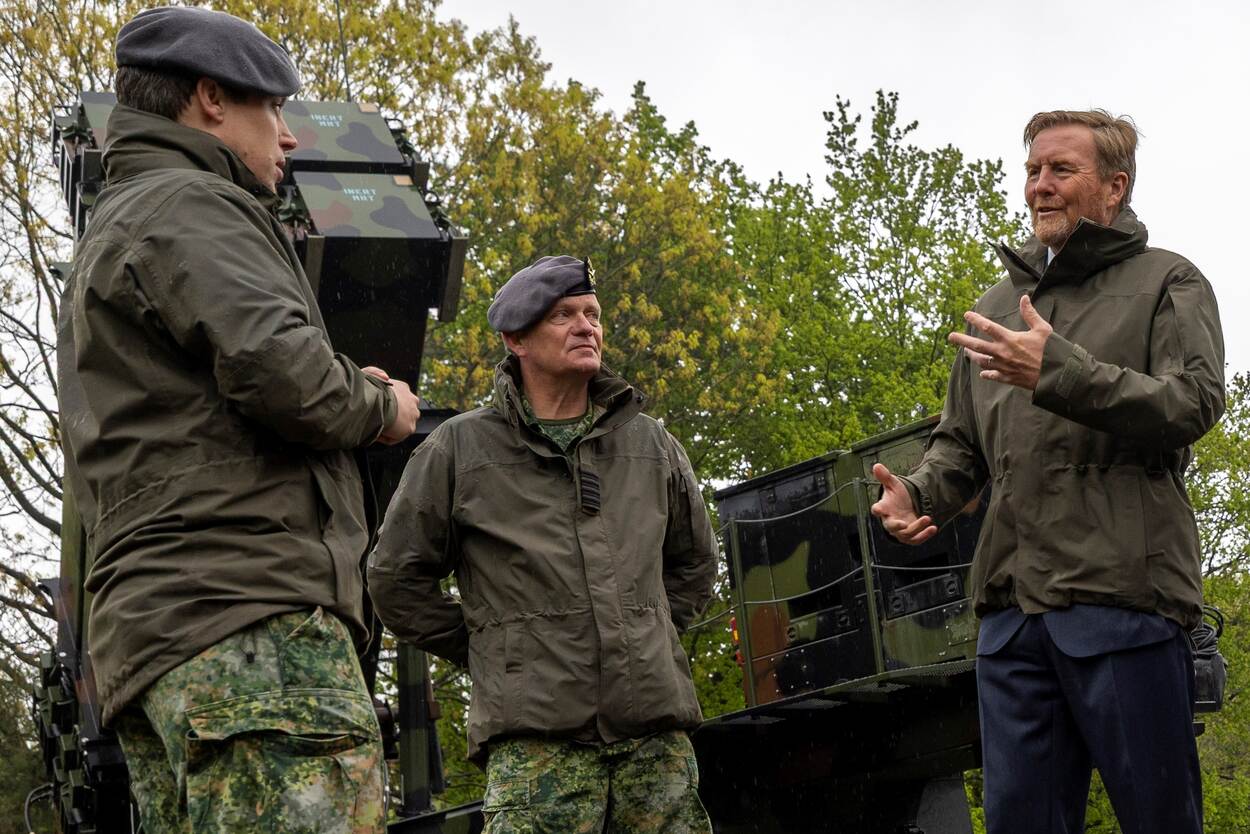 De koning luister in militair tenue naar een militair