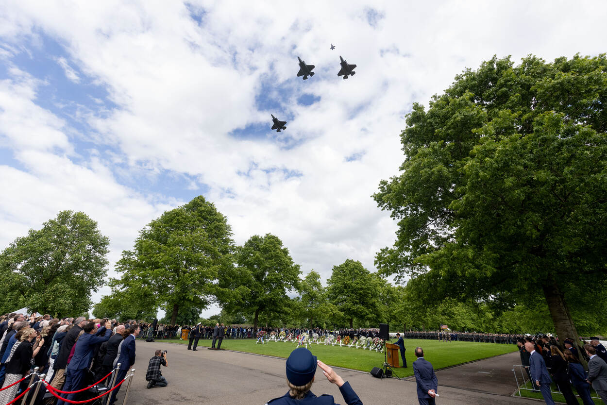 Aanwezigen kijken tijdens de herdenking in Margraten naar de lucht waar straaljagers overvliegen.