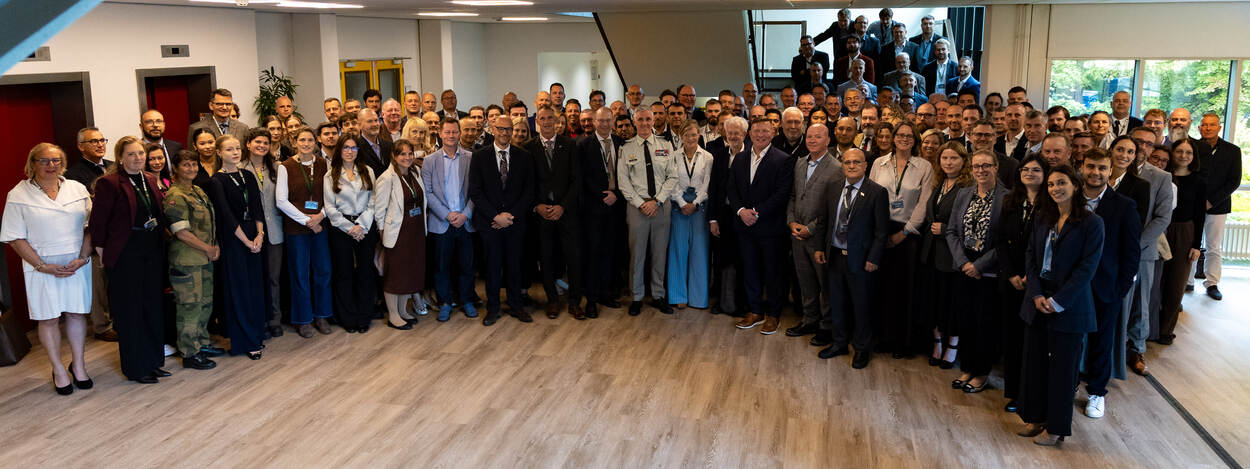 Meerdere mensen poseren in een open ruimte en op de trappen.