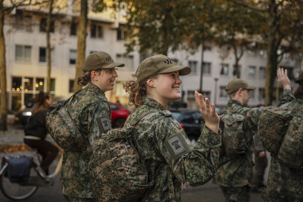 Twee jonge, vrouwelijke militairen in opleiding zwaaien naar omstanders.