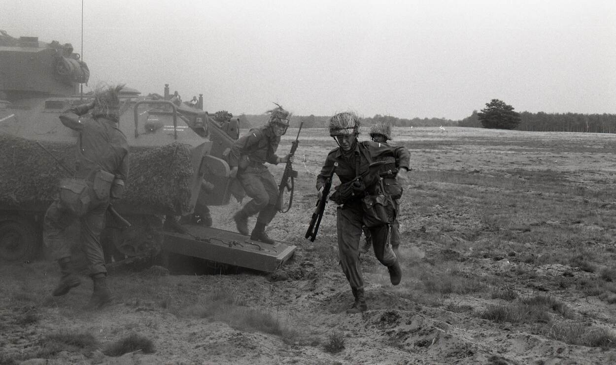 Pantserinfanteristen stormen uit hun rupsvoertuig.