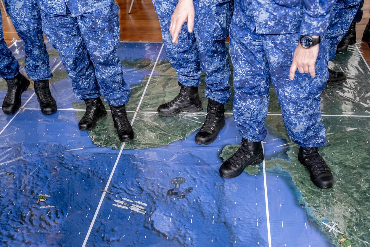 Marinemensen staan op een vloer waar een zeegebied op is uitgebeeld.