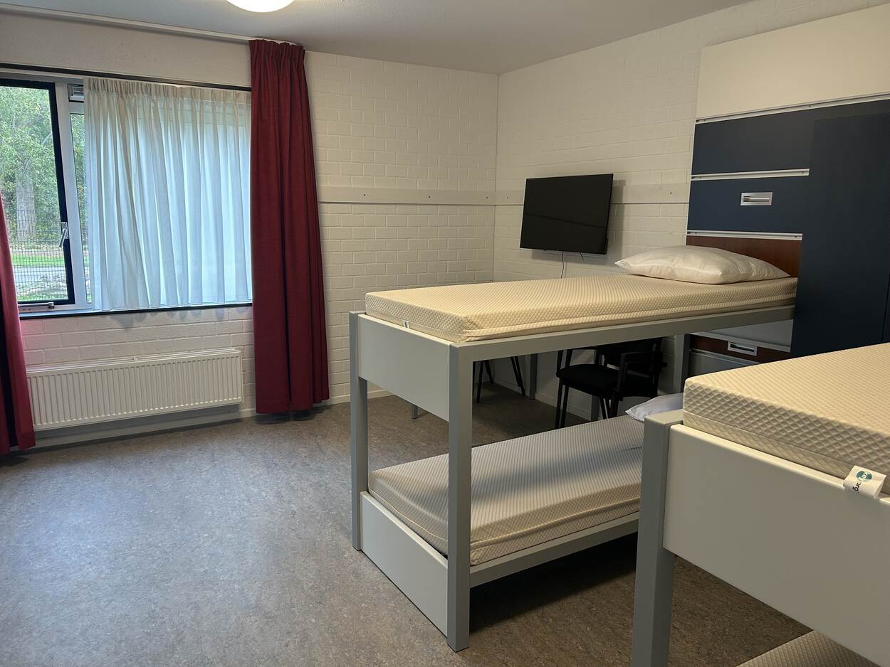 2 stapelbedden, een TV, ramen en een gordijn.