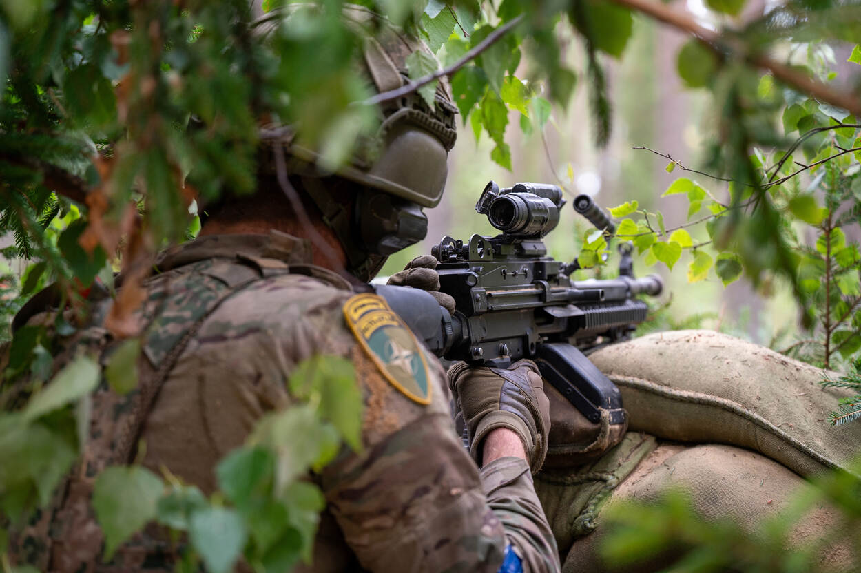 MILITAIR LAAT ZIJN WAPEN RUSTEN OP ZANDZAKKEN.