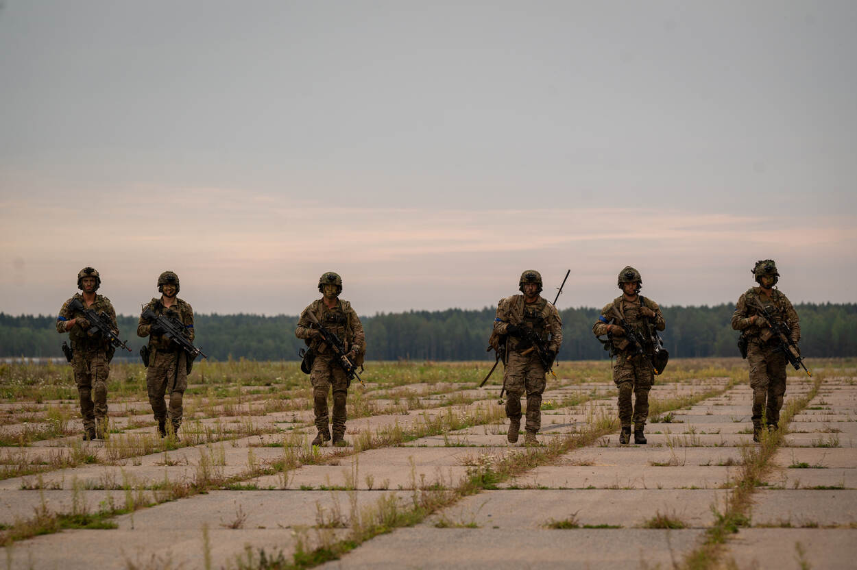 MILITAIREN LOPEN NAAST ELKAAR OVER EEN VELD.