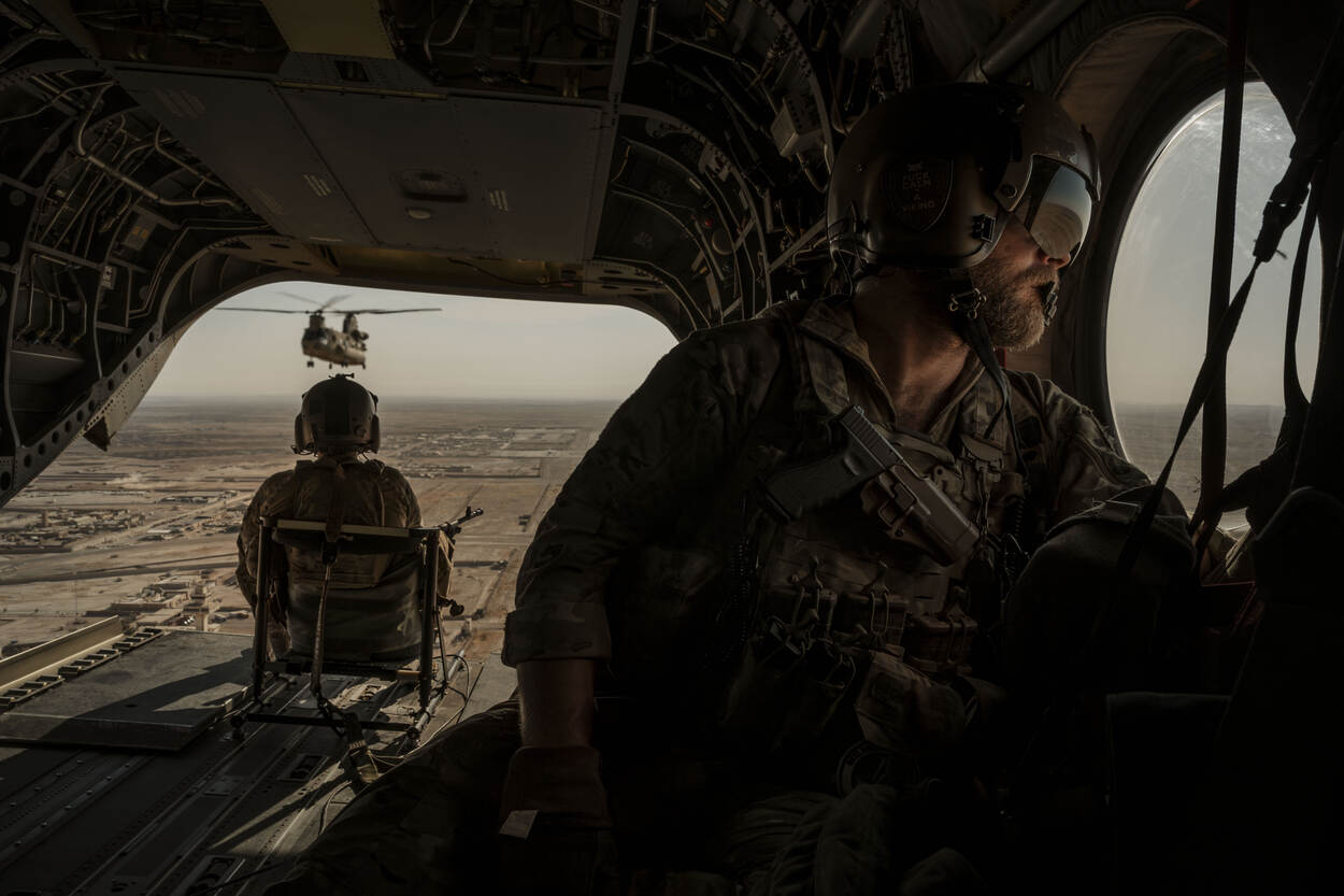 Doorgunners kijken vanuit de helikopter naar het gebied beneden hen.