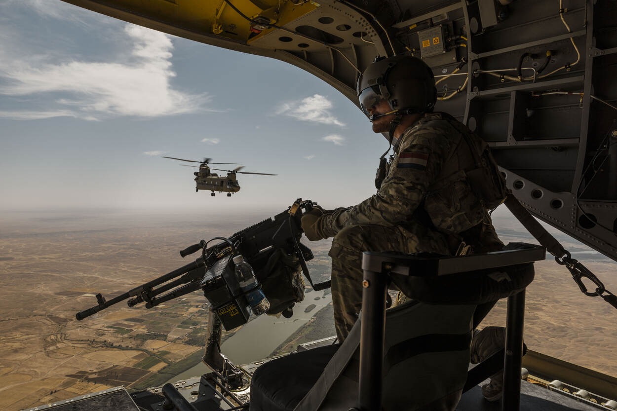 Boven Irak kijkt een militair vanuit een Chinook naar beneden.