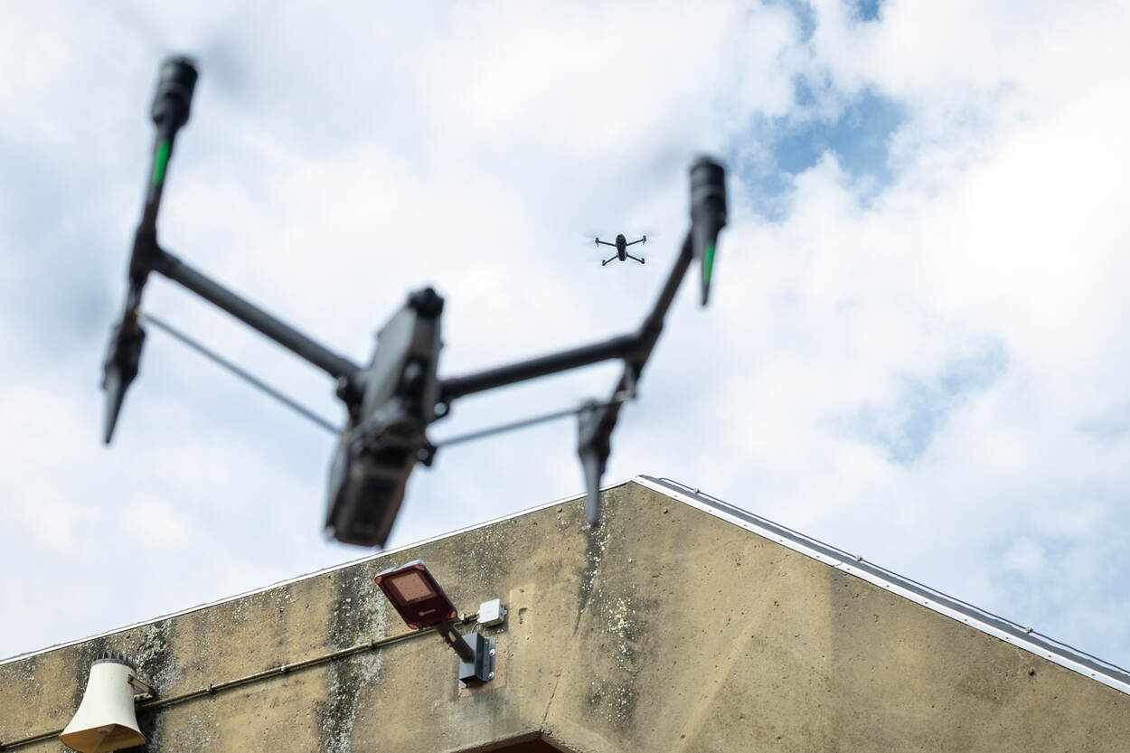 Twee drones hangen boven een oude betonnen hangaar.