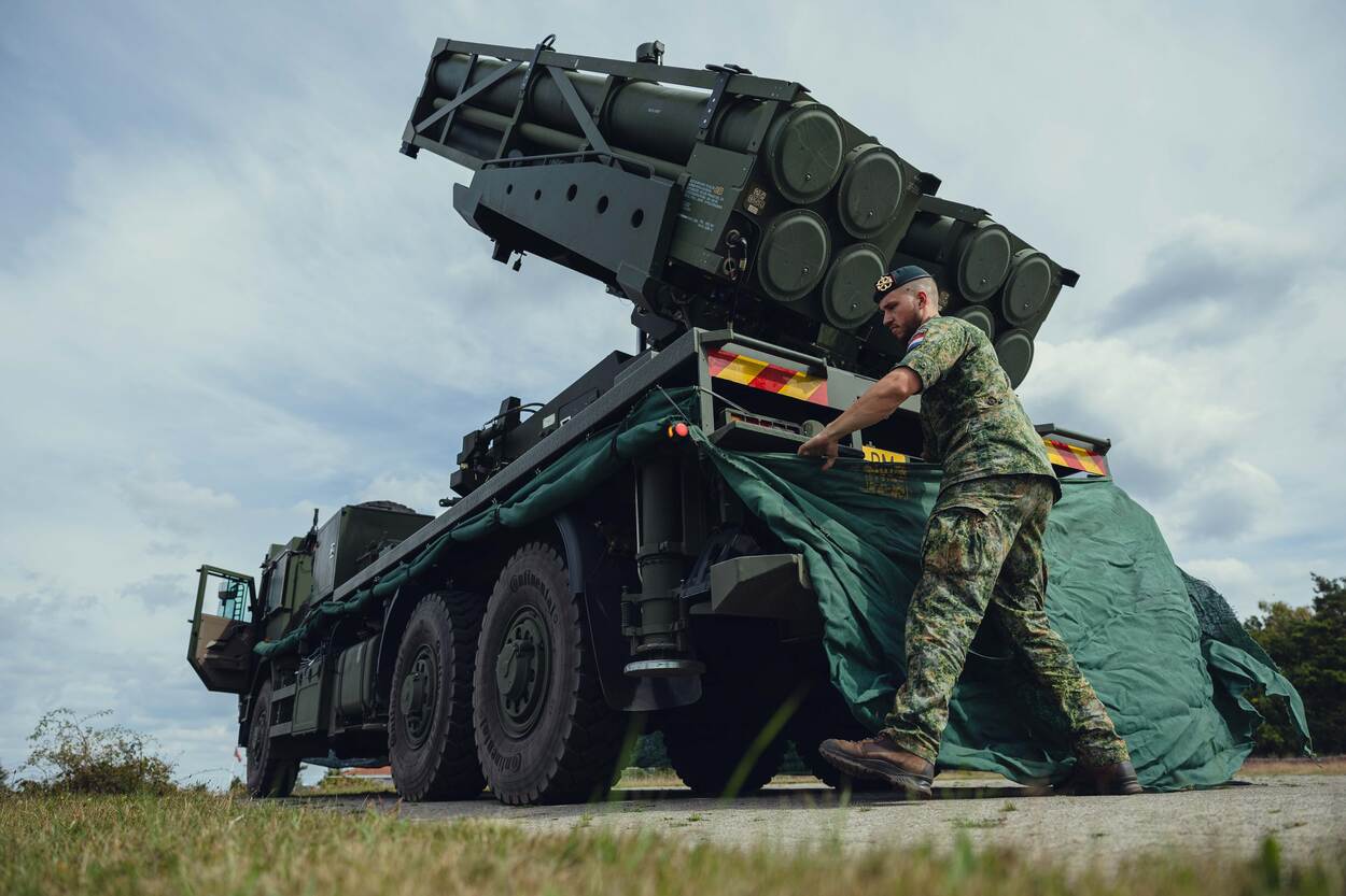 Een militair bevestigt een gronddoek rondom een raketlanceerinstallatie.