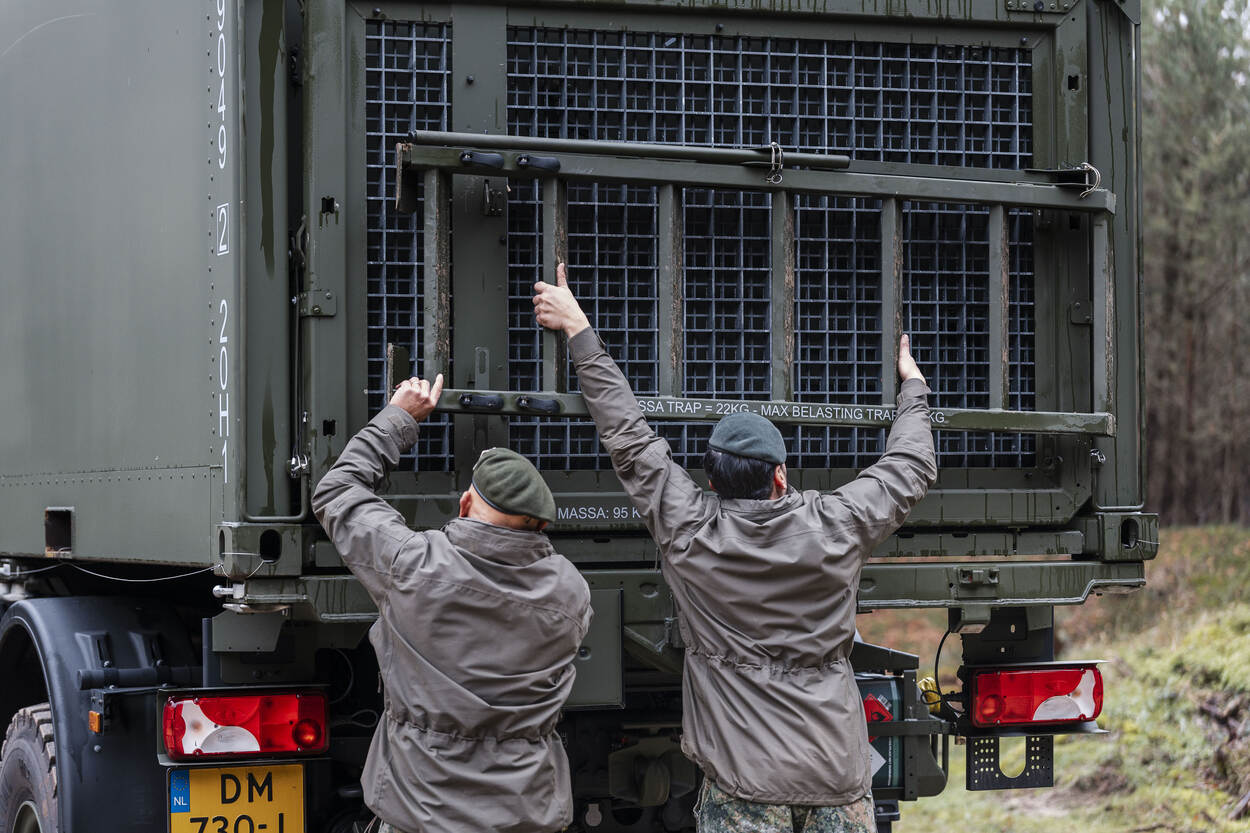 twee militairen die aan de achterzijde van de shelter de trap gereedmaken voor transport.