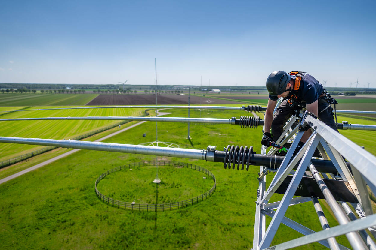 Monteur van Antennegroep controleert radioantenne op 35 meter hoogte.