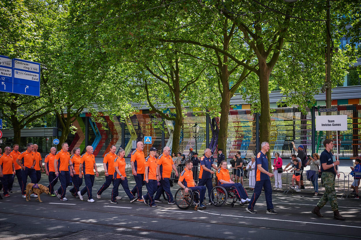 Militairen in oranje trainingspakken lopen voorbij.