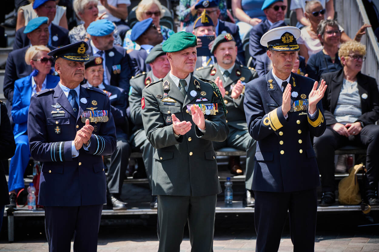 Drie militairen applaudisseren.