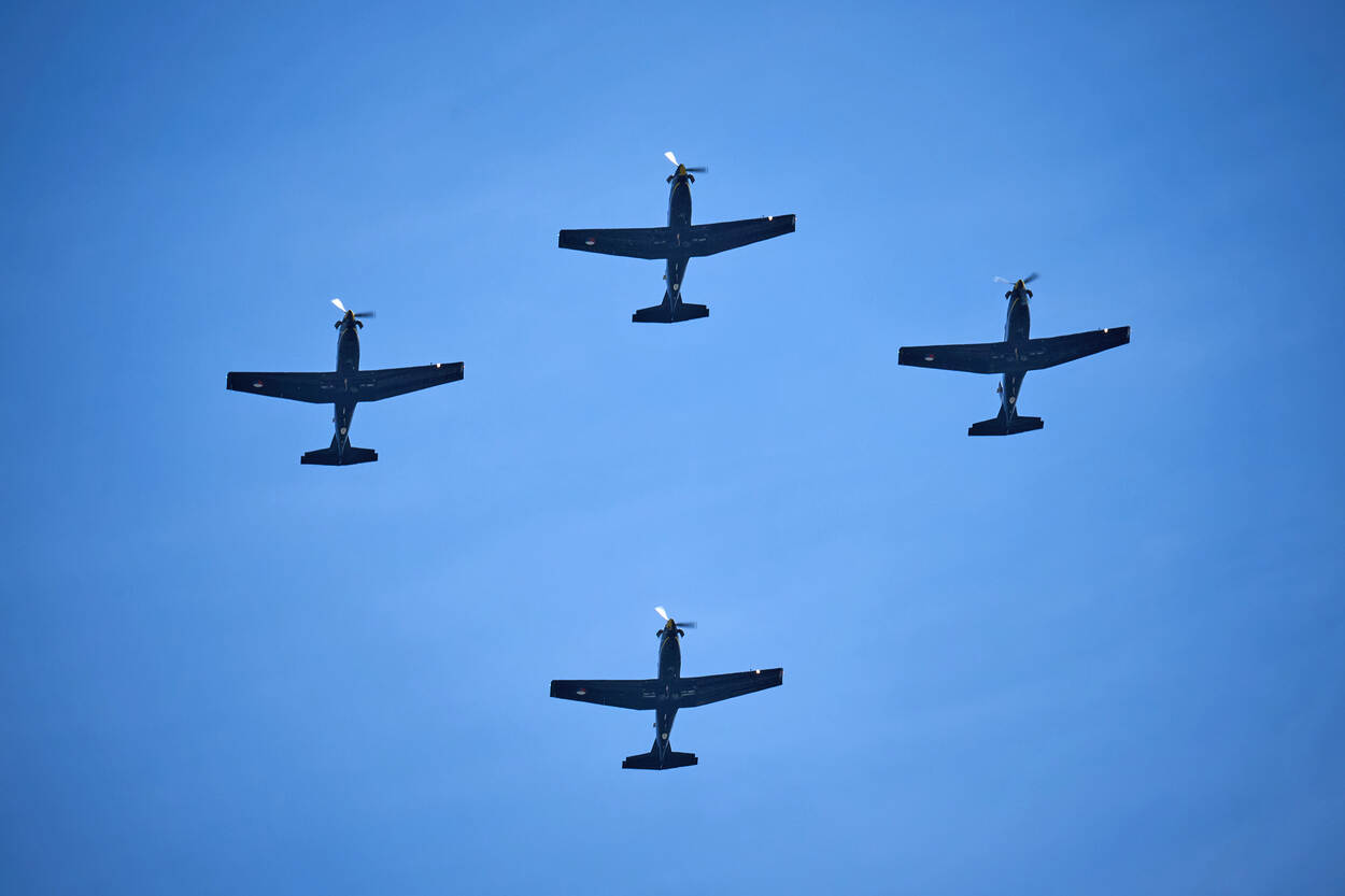 Een formatie van vier PC-7’s tegen een blauwe lucht.