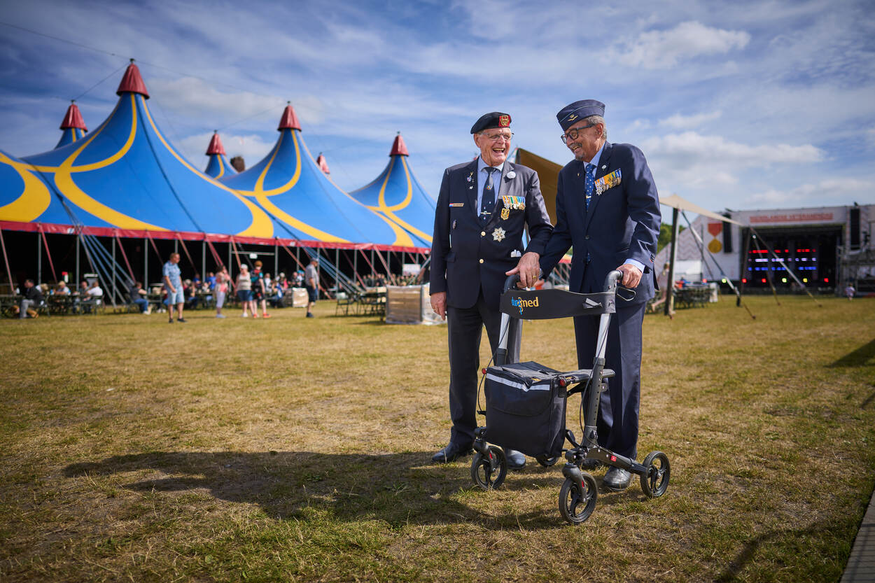 Een luchtmacht- en een landmachtveteraan staan lachend voor een tent.