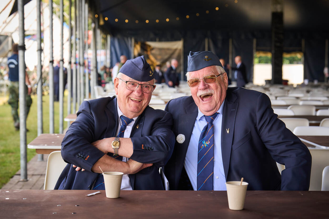 Twee luchtmachtveteranen zitten lachend aan een tafel.