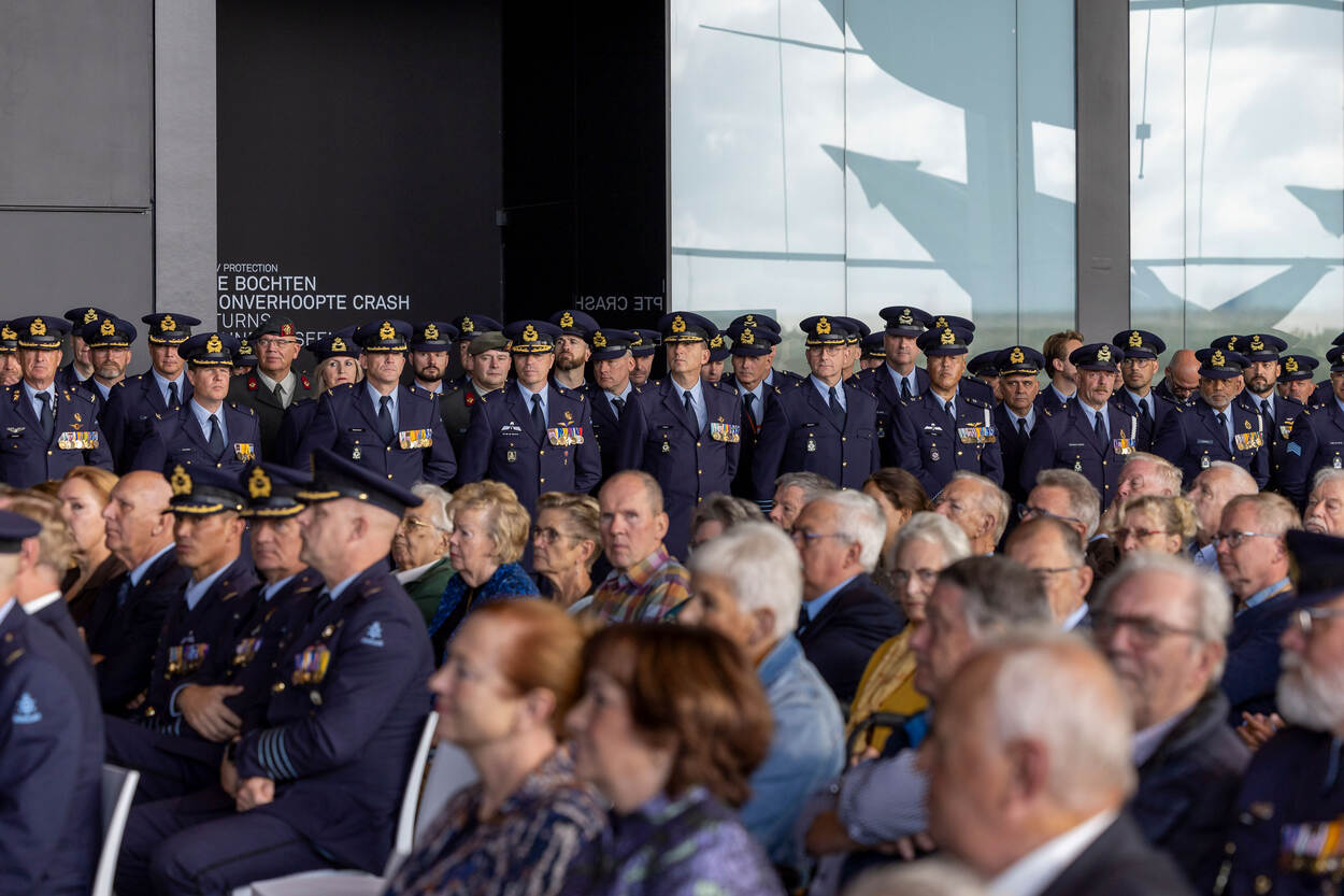 Op de voorgrond zittende bezoekers, op de achtergrond staand tientallen actief dienende militairen in uniform.