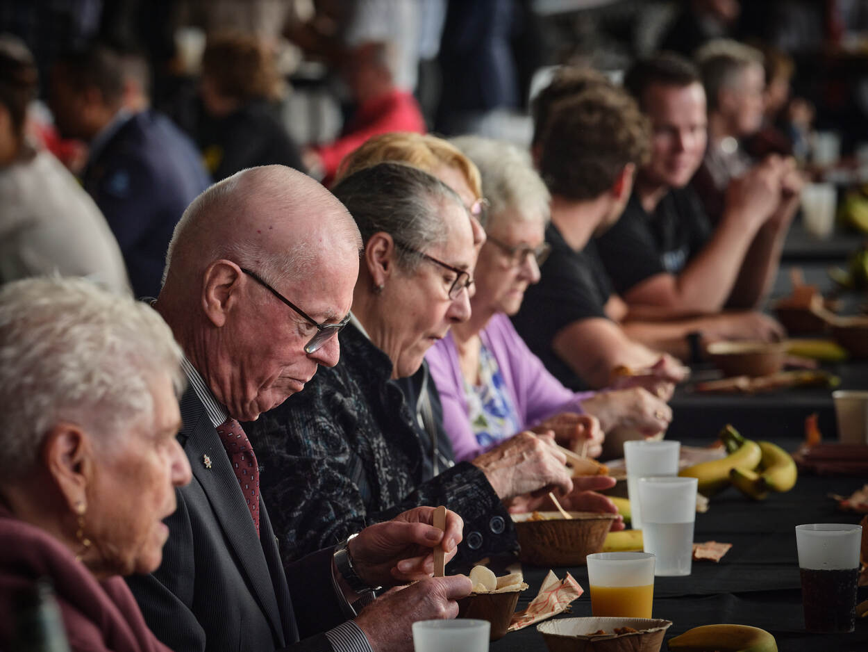 Bezoekers eten rijstmaaltijd aan lange tafel.