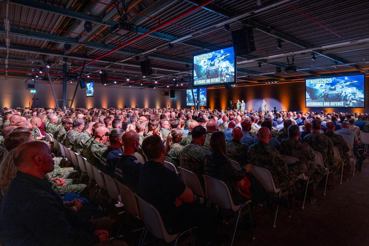 Rijen mensen zitten in een congreszaal.