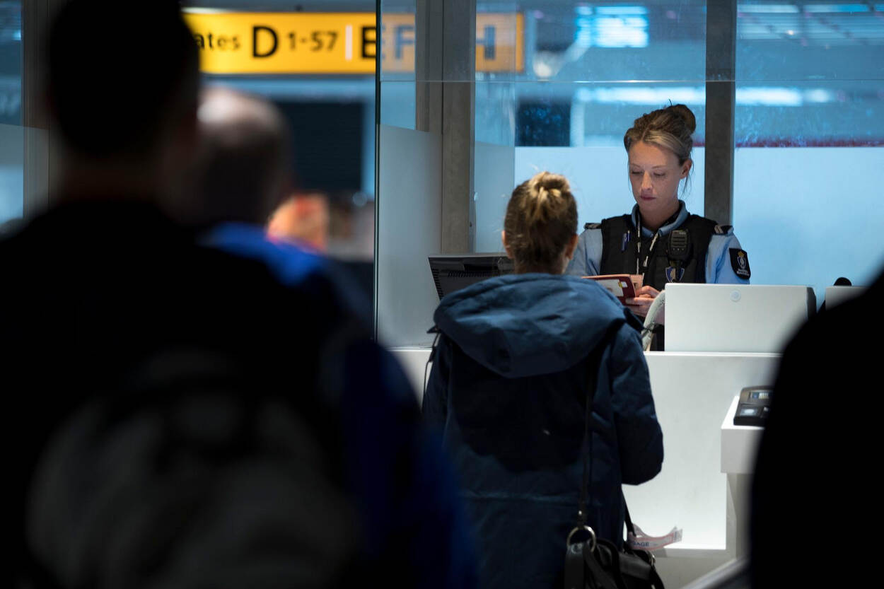 Een marechaussee controleert reisbescheiden bij een doorlaatpost.