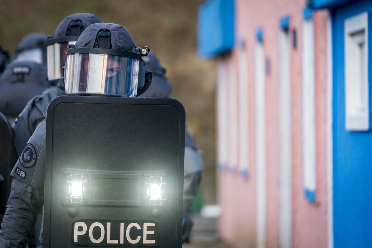 Leden van een AT kijkend door hun ballistische schild.