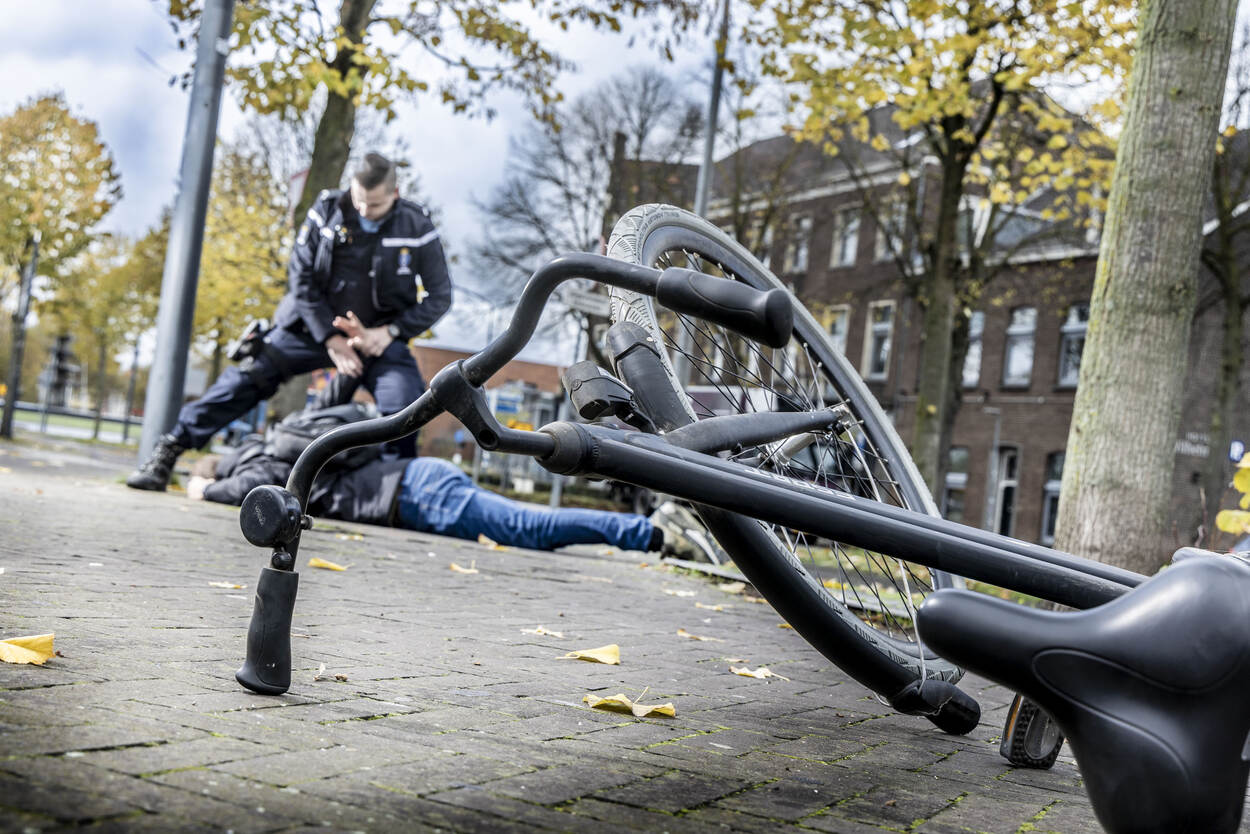 Een marechaussee boeit een verdachte, fiets op voorgrond.