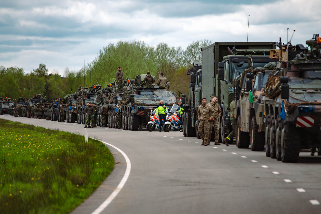 Motorcollega’s van de Marechaussee tussen de militaire voertuigen op de openbare weg.