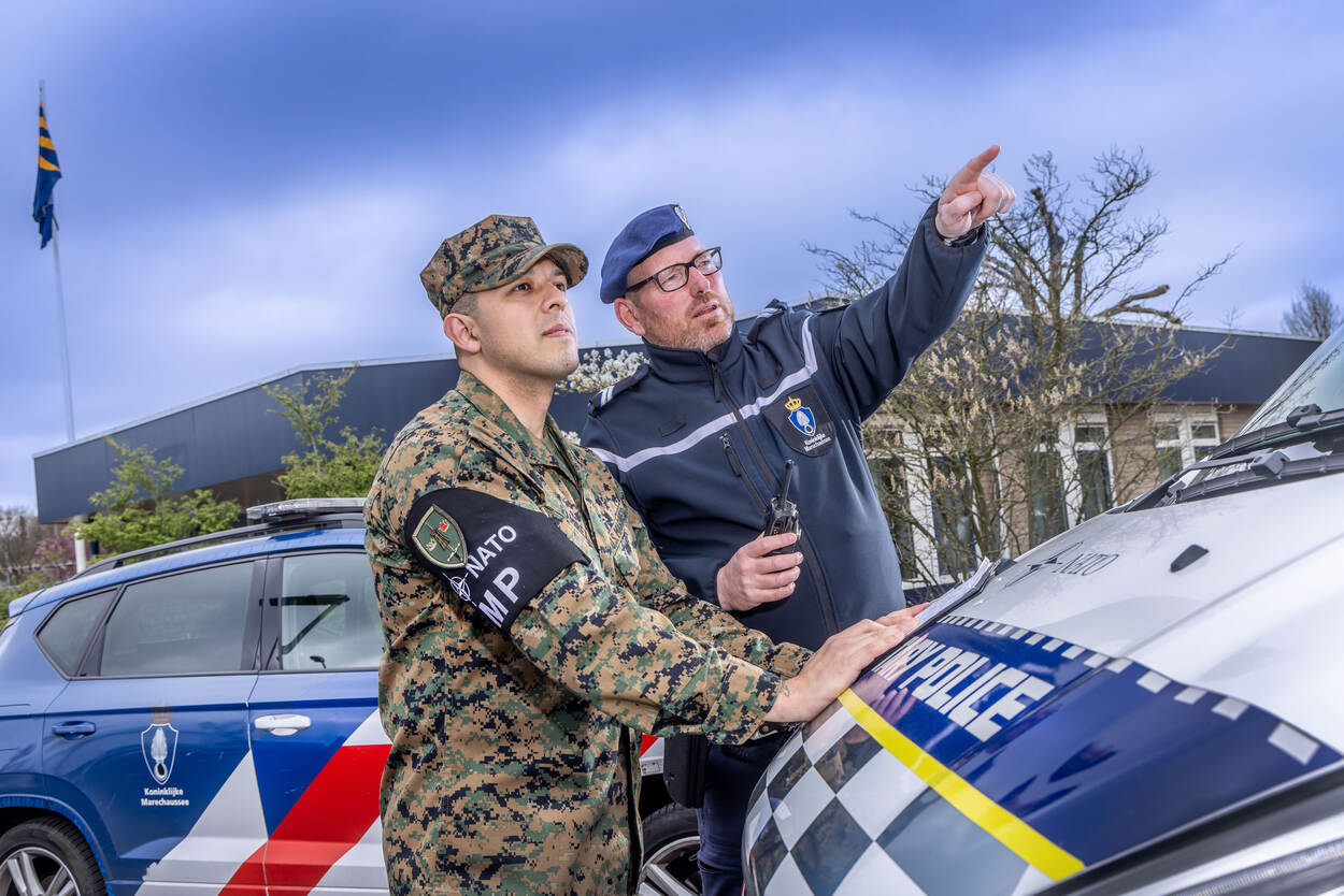 Een Nederlandse Marechaussee overlegt met een Amerikaanse collega.