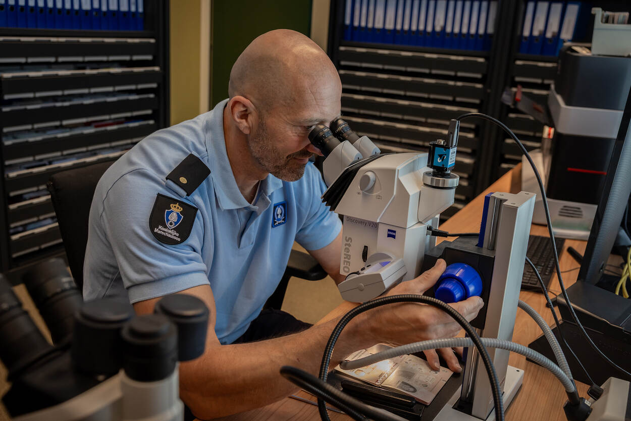 Een paspoort wordt minutieus onder een microscoop gecontroleerd.