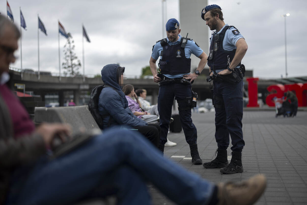 Twee marechaussees spreken een persoon aan op Schiphol.