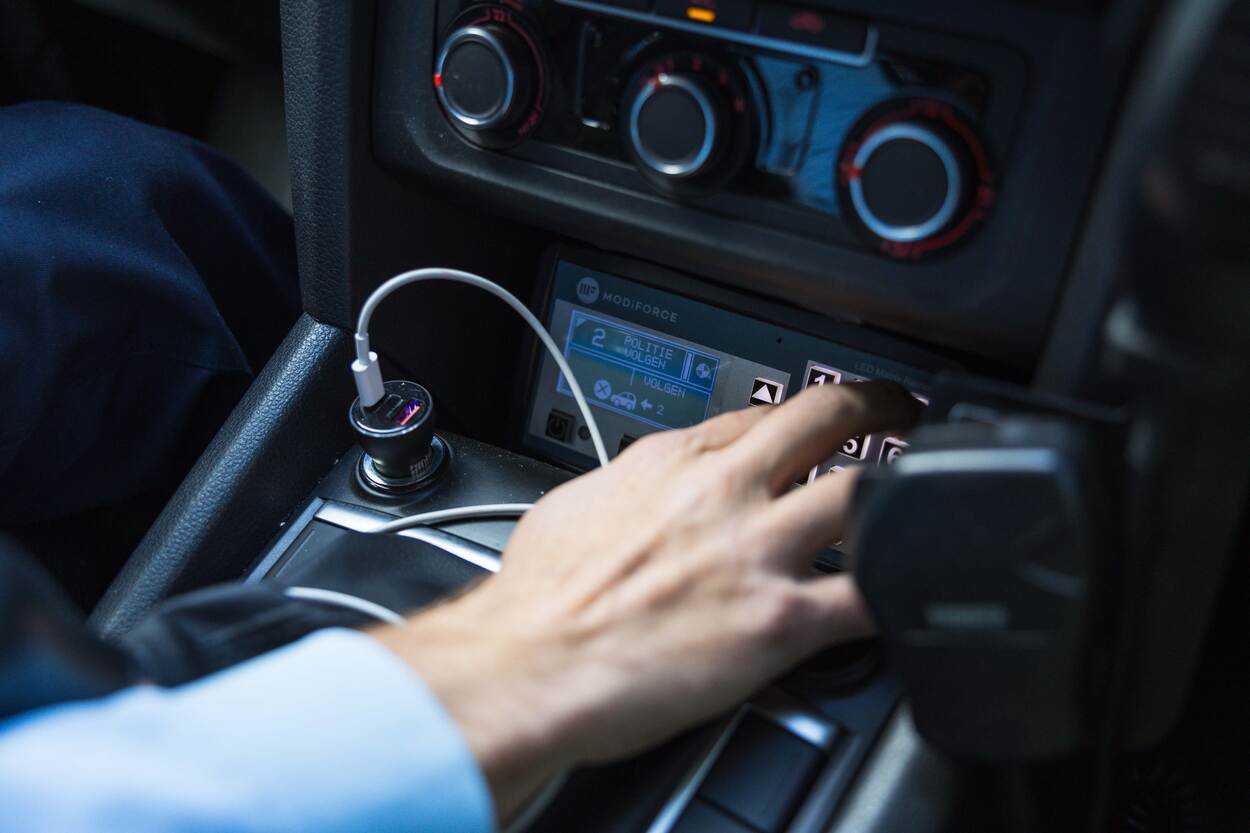 Een marechaussee bedient de signalering in het voertuig.