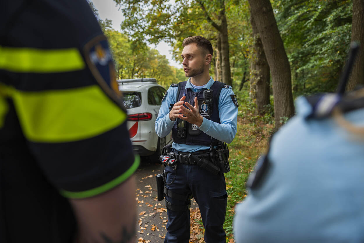 Een marechaussee legt iets uit aan 2 collega van de KMar en de politie.