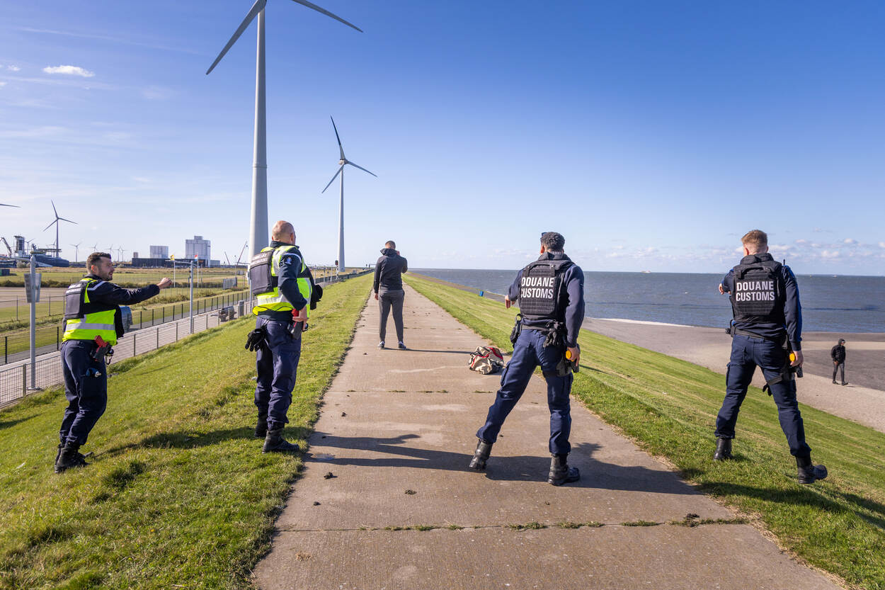 Een verdachte staat met zijn rug naar marechaussees en douanemedewerkers.