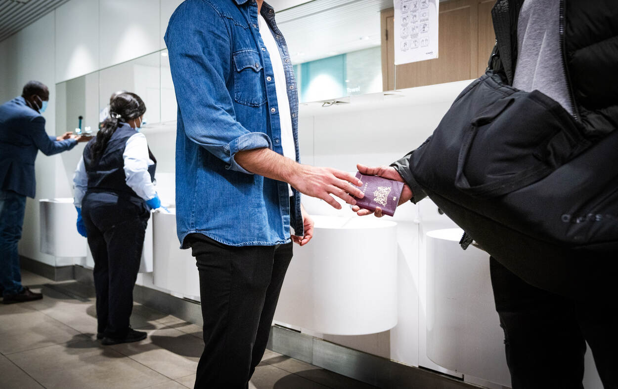 Man overhandigt Nederlands paspoort aan andere man