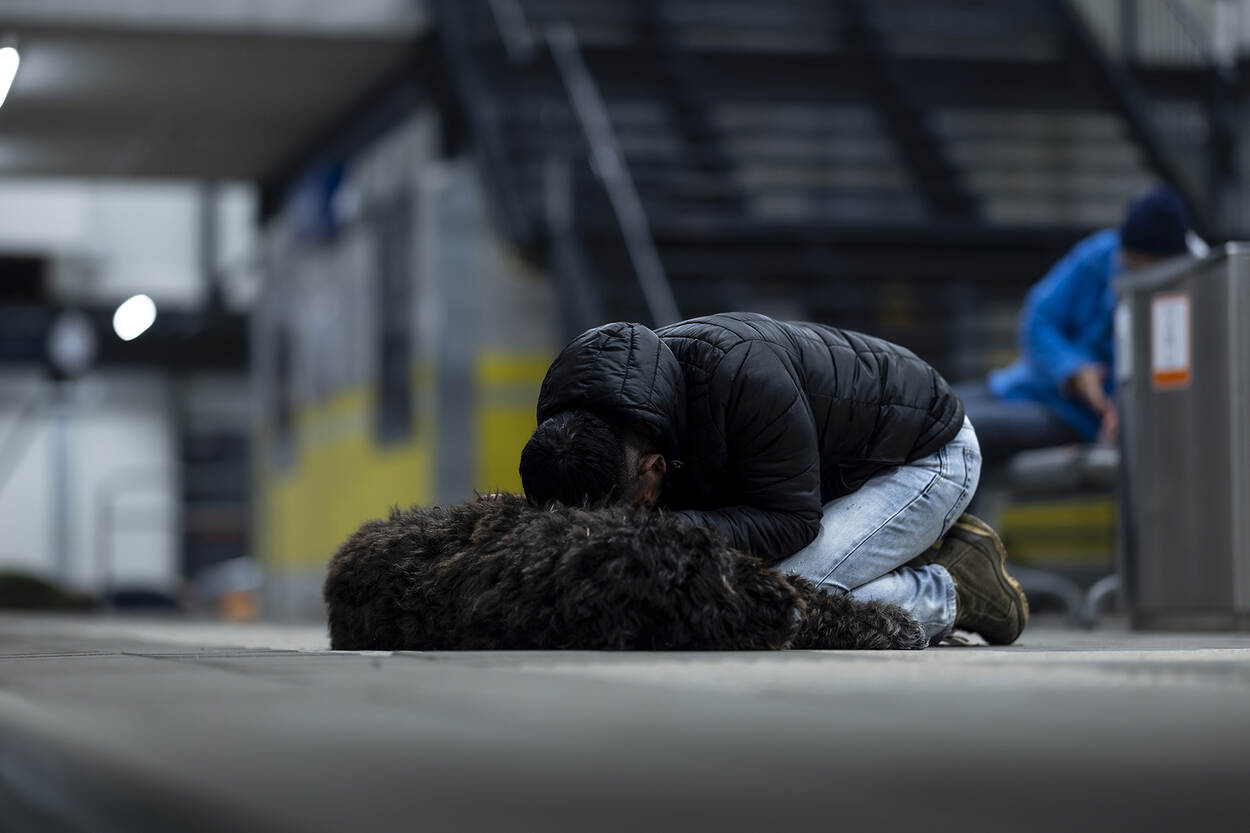 Een slachtoffer treurt geknield bij z’n overleden huisdier op het perron.